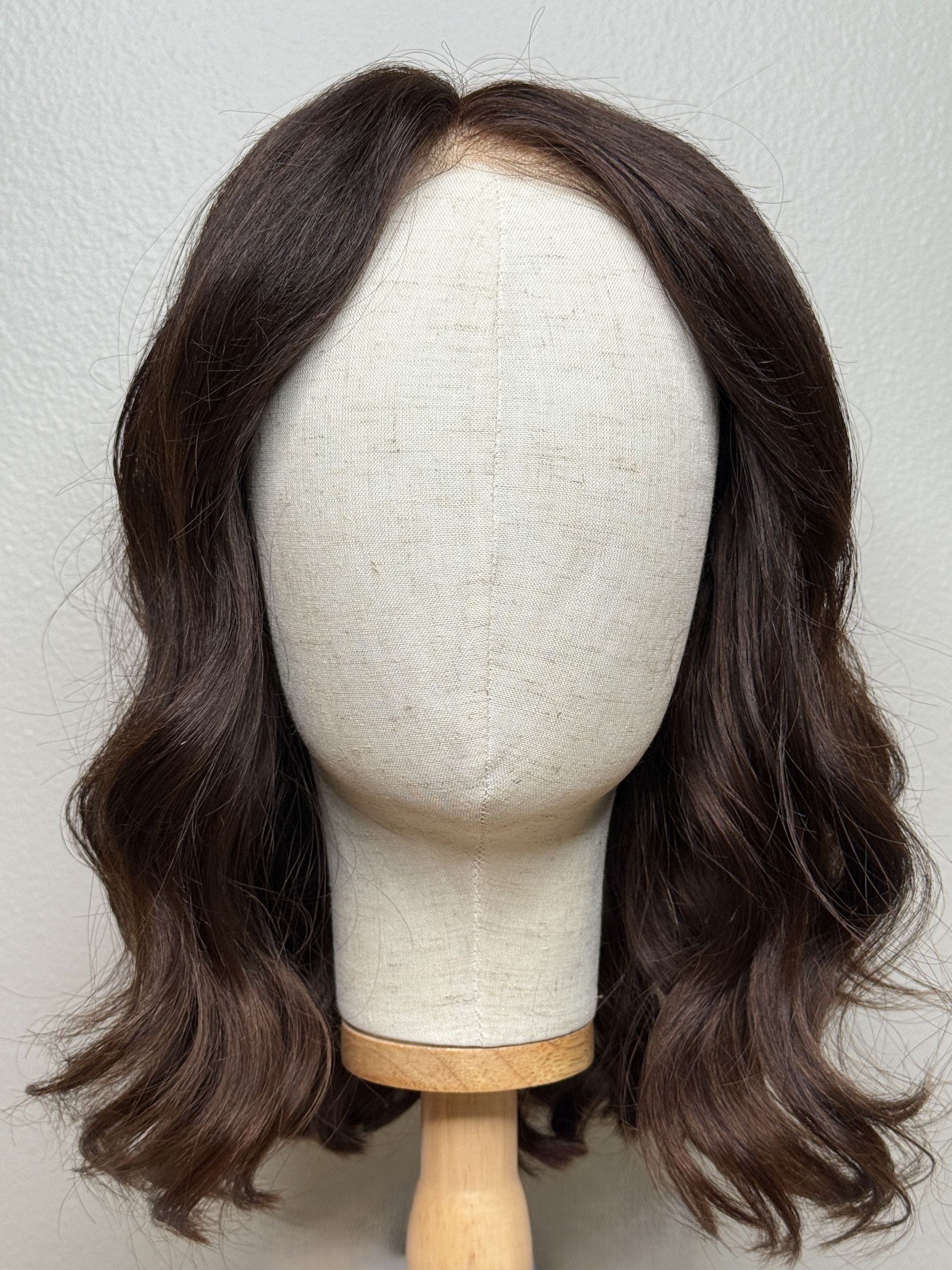 Brown wig styled with loose waves on a mannequin head, centered.