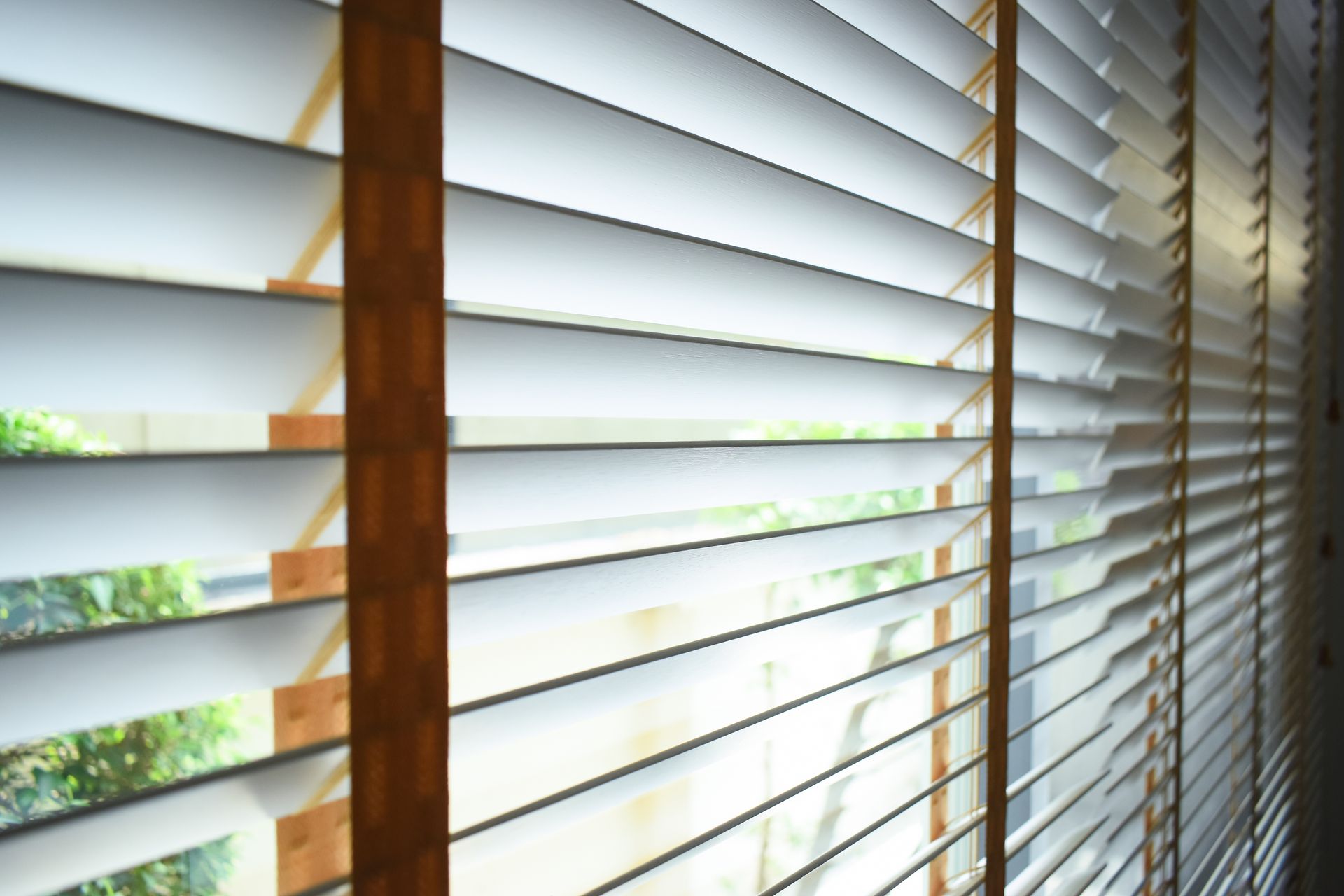 A man wearing a hard hat is installing blinds on a window.