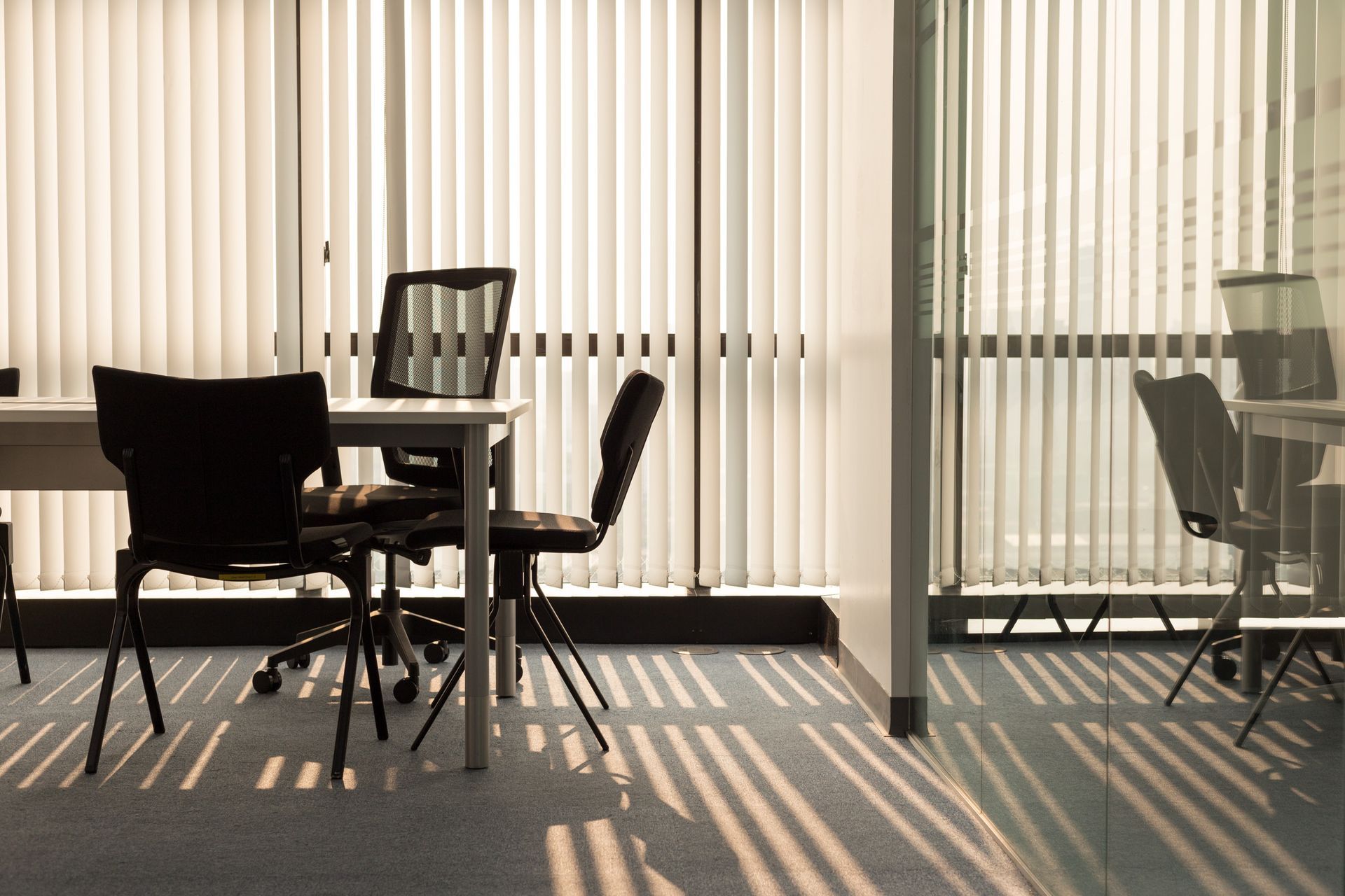 A conference room with a table and chairs and blinds on the windows.