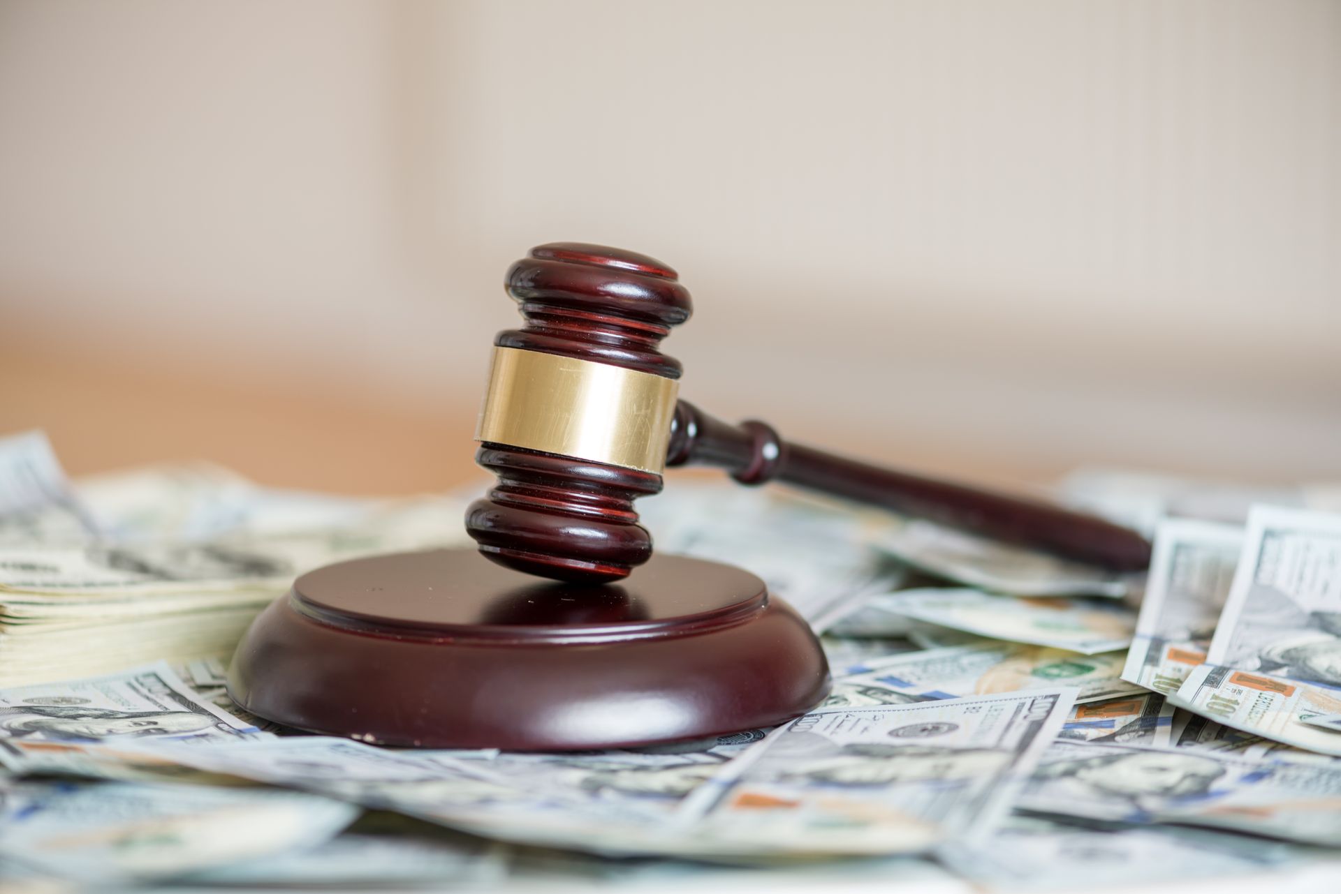 Gavel on a wooden block atop a pile of US dollar bills.