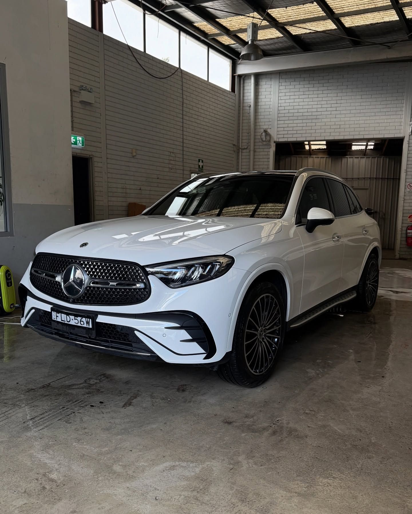 White Mercedes GLC coupe parked inside a garage with dark wheels and a black grille.