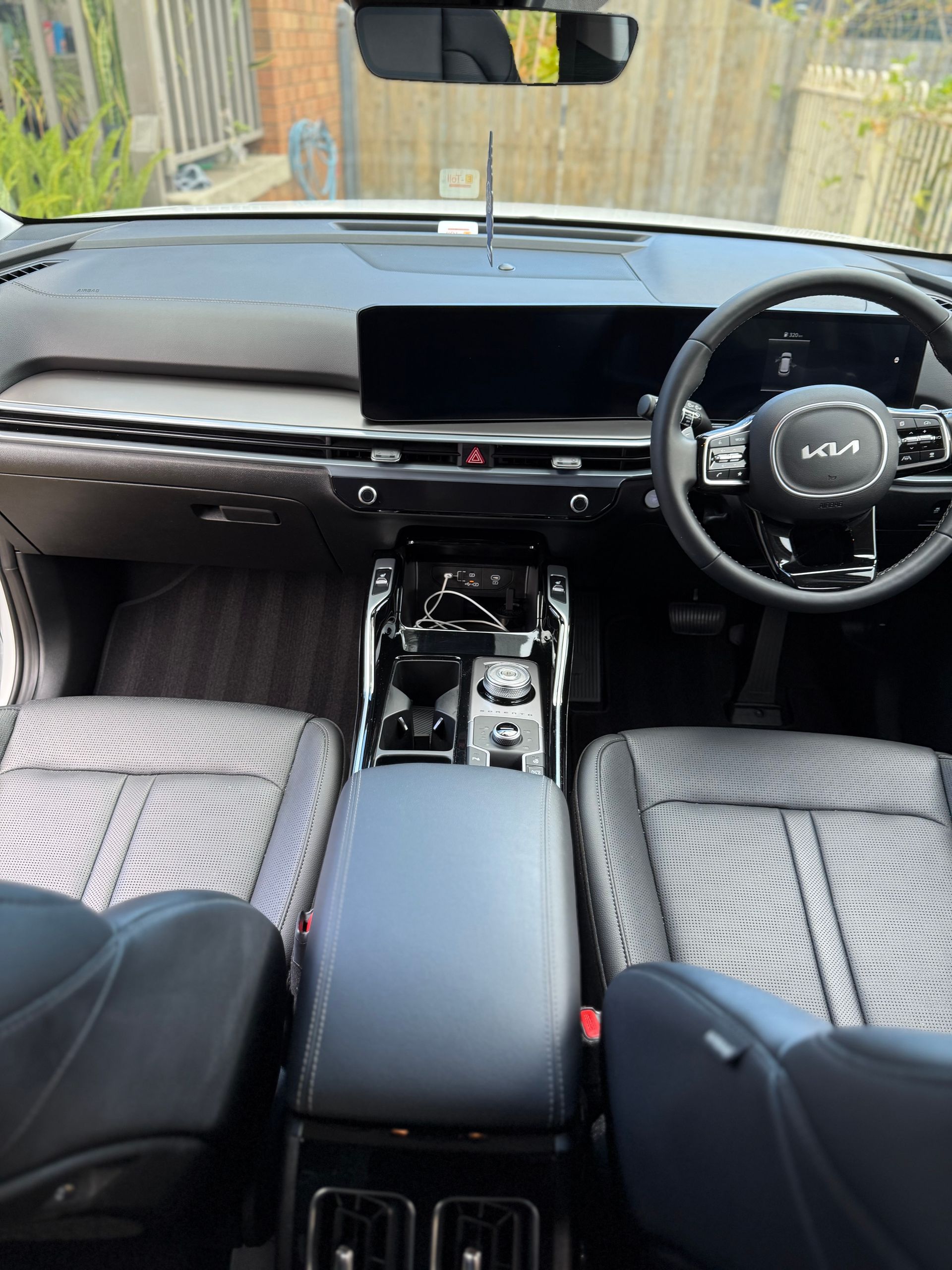 Interior view of a Kia car. Gray and black seats, steering wheel, dashboard, and center console are visible.