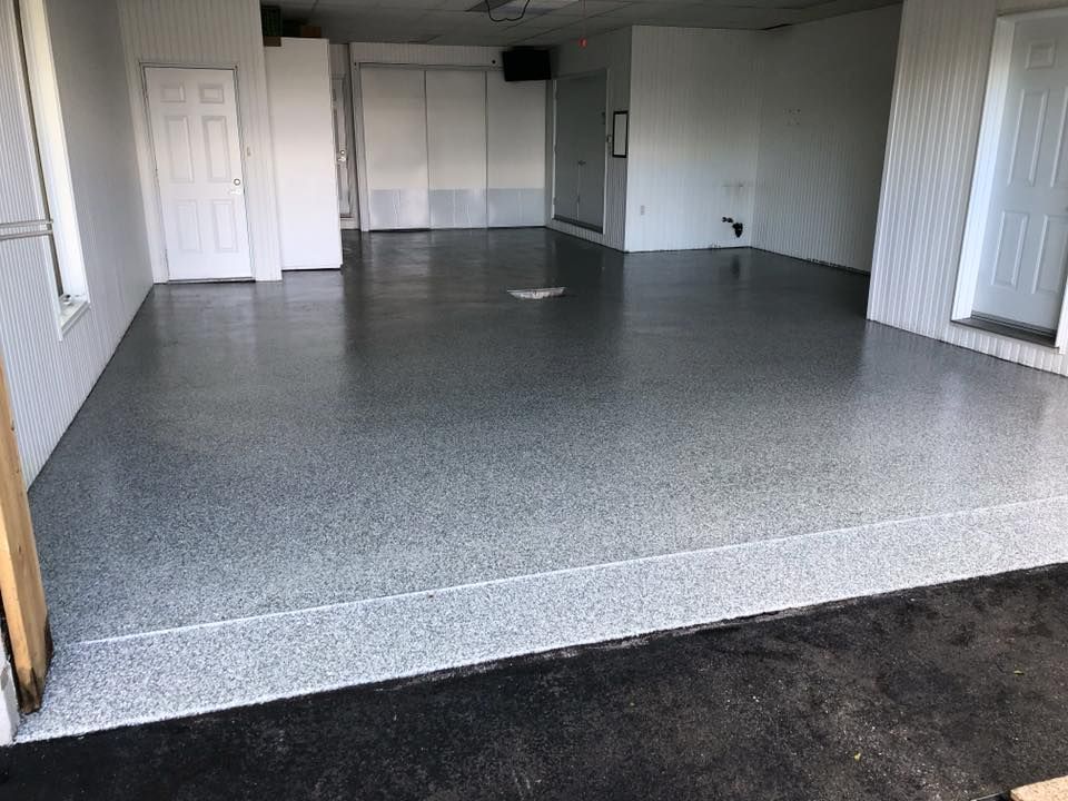 Un garage avec un sol gris et des murs blancs.