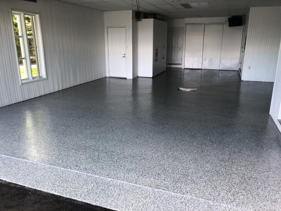 Une grande pièce avec un sol gris et des murs blancs.