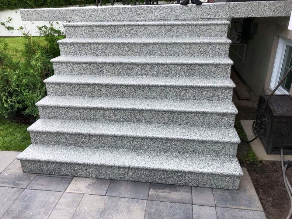 Un ensemble d'escaliers en granit posés au sommet d'un patio.