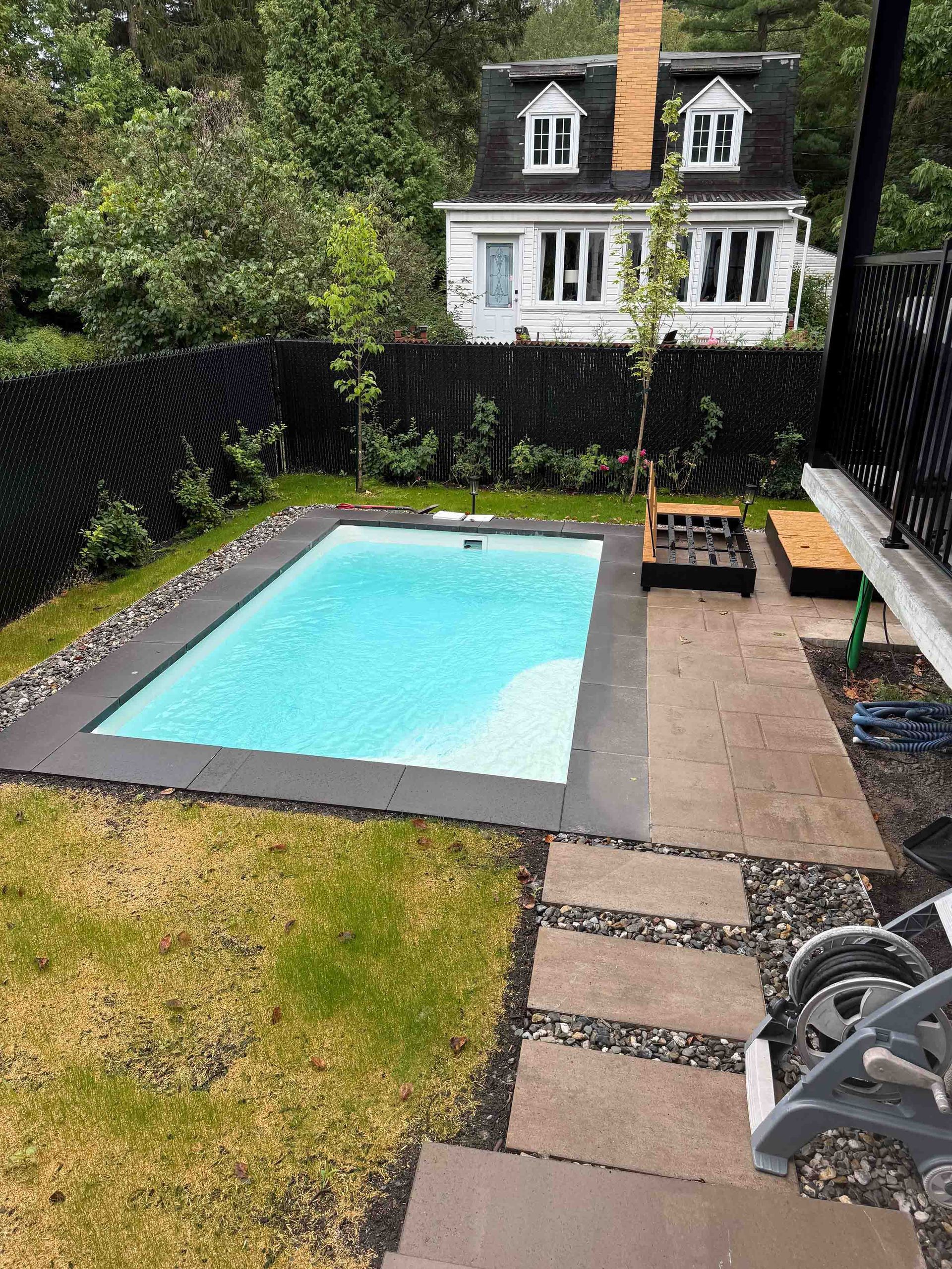 Cour arrière avec piscine clôturée, patio, pelouse et maison en arrière-plan