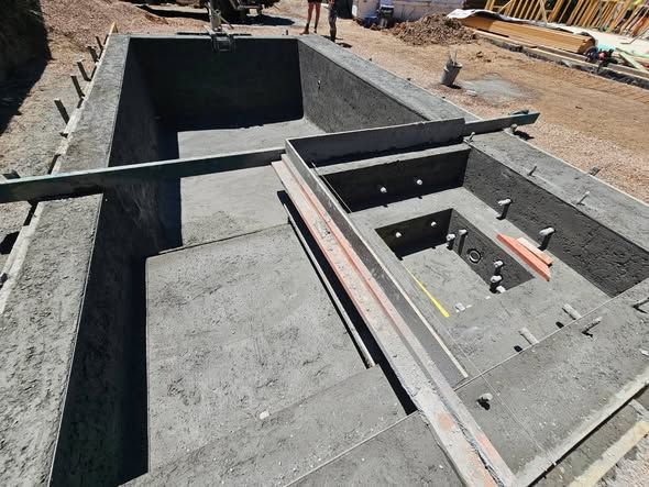 Construction site with concrete foundation walls and a rectangular pit under construction
