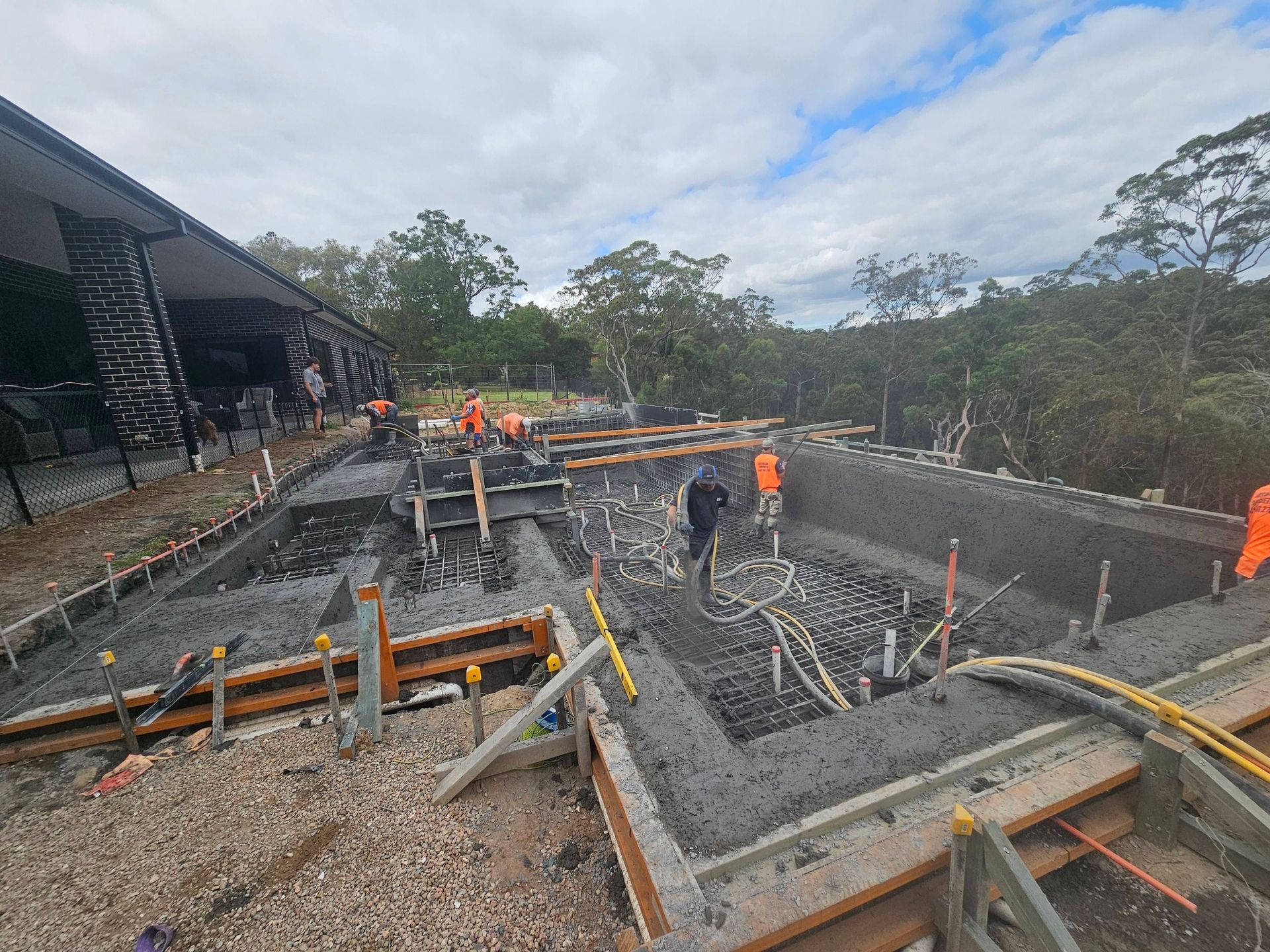 Workers pour concrete for a building foundation at a construction site.