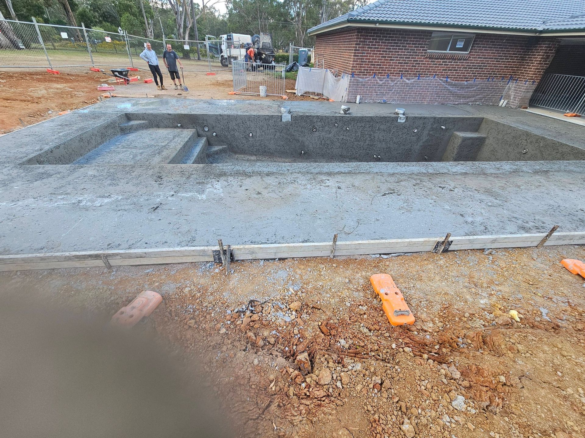 Concrete foundation pit at a construction site with workers in the background