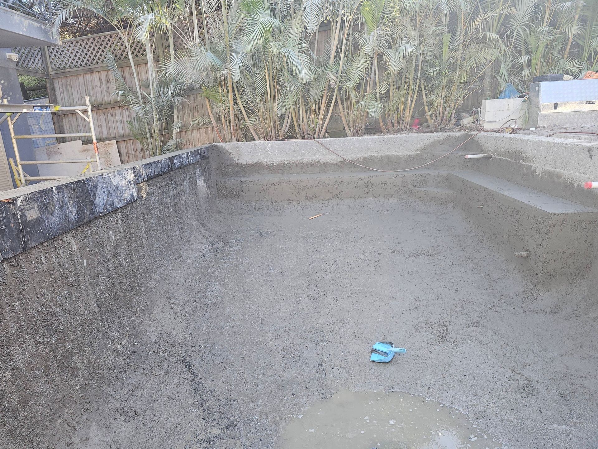 Empty concrete water tank with a small blue object on the floor and trees in the background