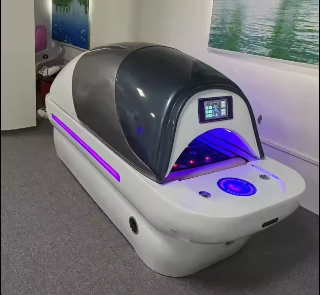 Futuristic white wellness pod with dark dome and purple lighting in a spa room