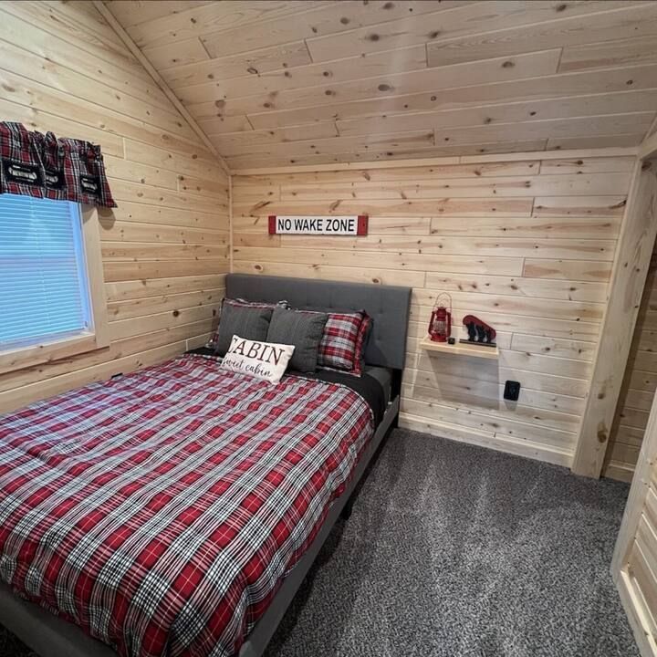 Cozy bedroom with a plaid bedspread, wooden walls, and a