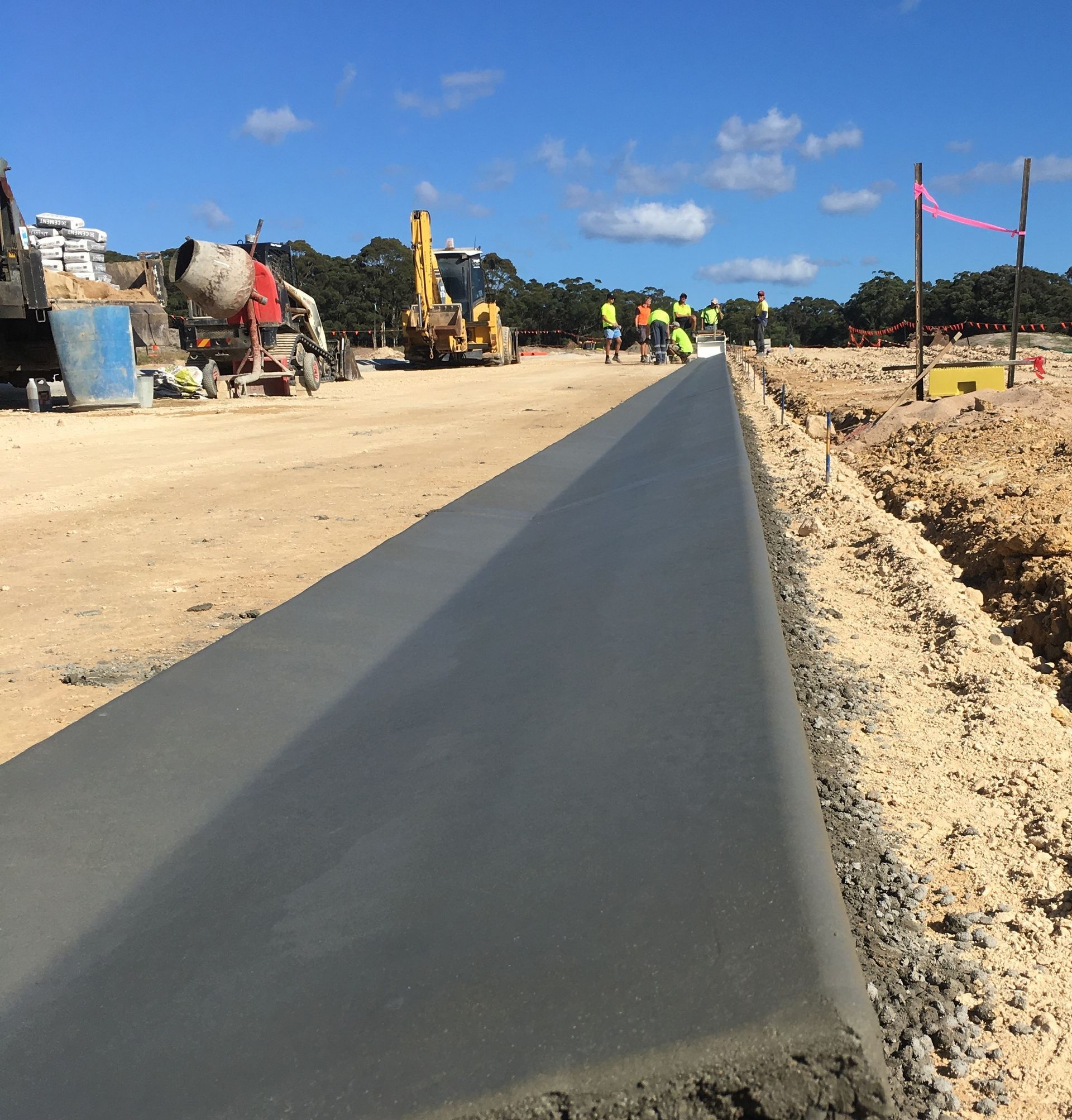 A concrete road is being built in a dirt field