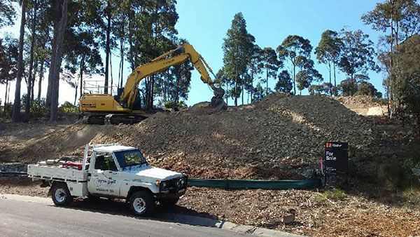 A truck is parked on the side of the road next to a pile of dirt.