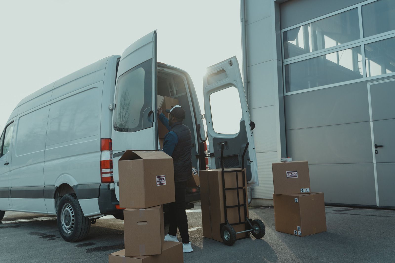 A person loads boxes into a white delivery van near a loading dock.