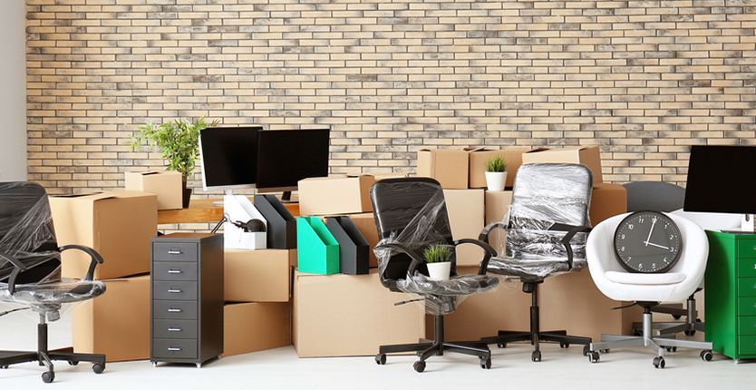 Office with packed boxes, desk, chair, and large window.