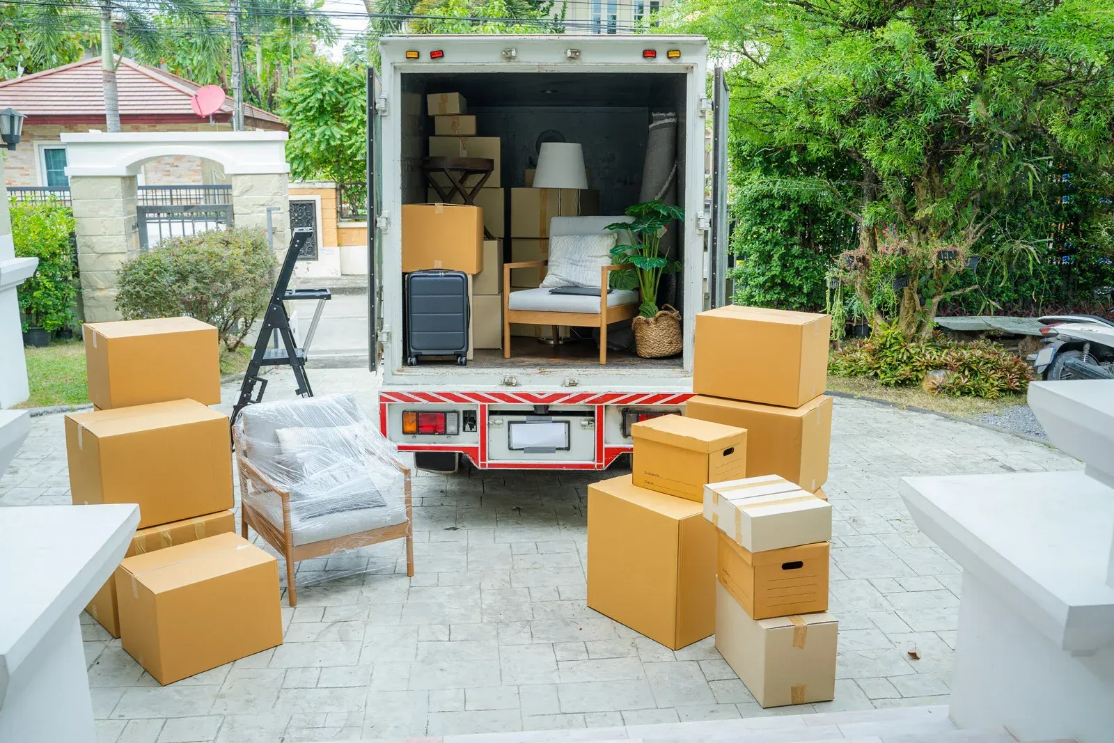Boxes and furniture loaded into a moving truck in front of a house.