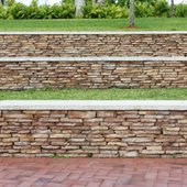 Stone retaining wall with grass above and red brick pavement in front