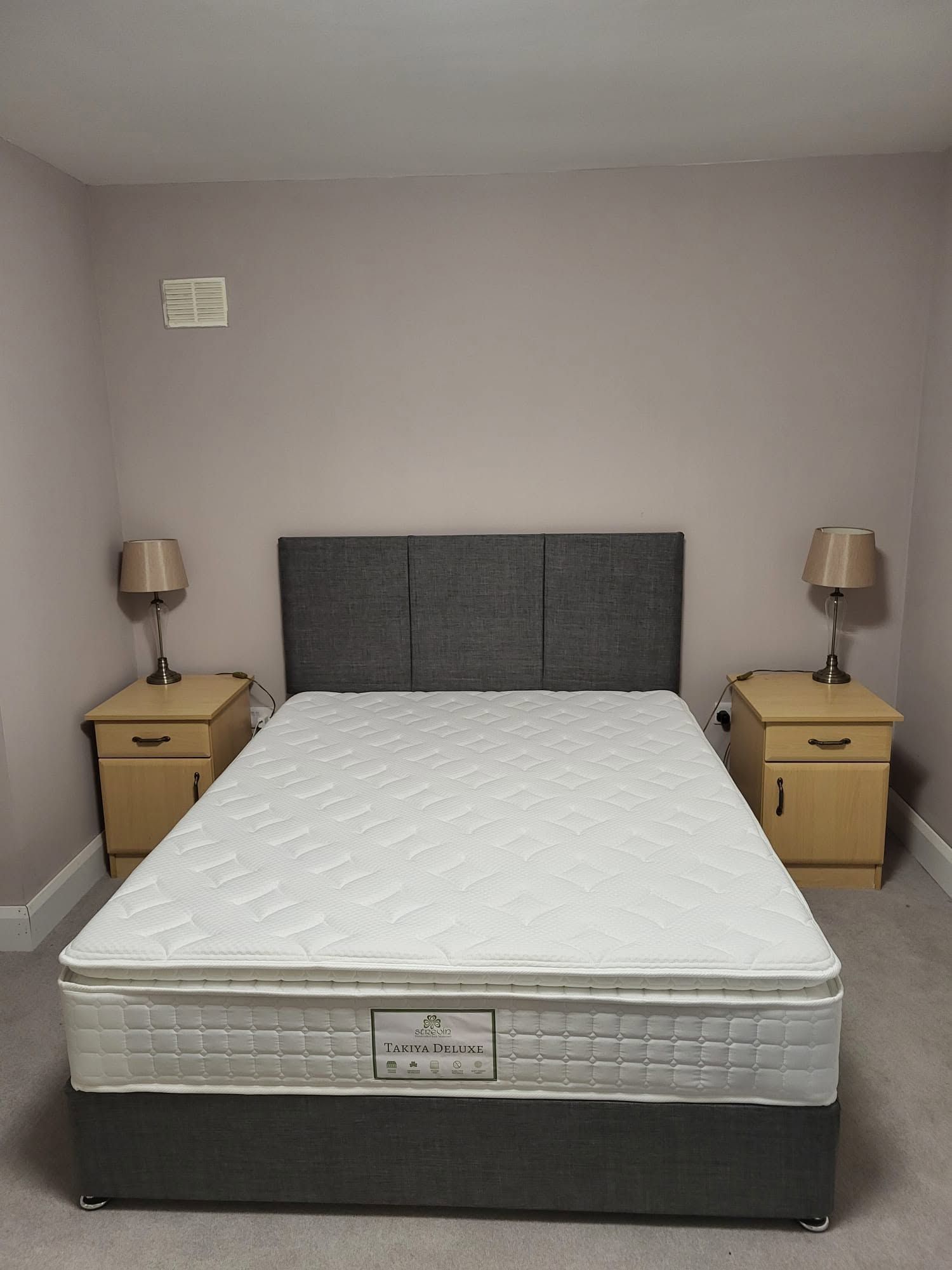 Simple bedroom with a bed centered between two nightstands and lamps on each side.