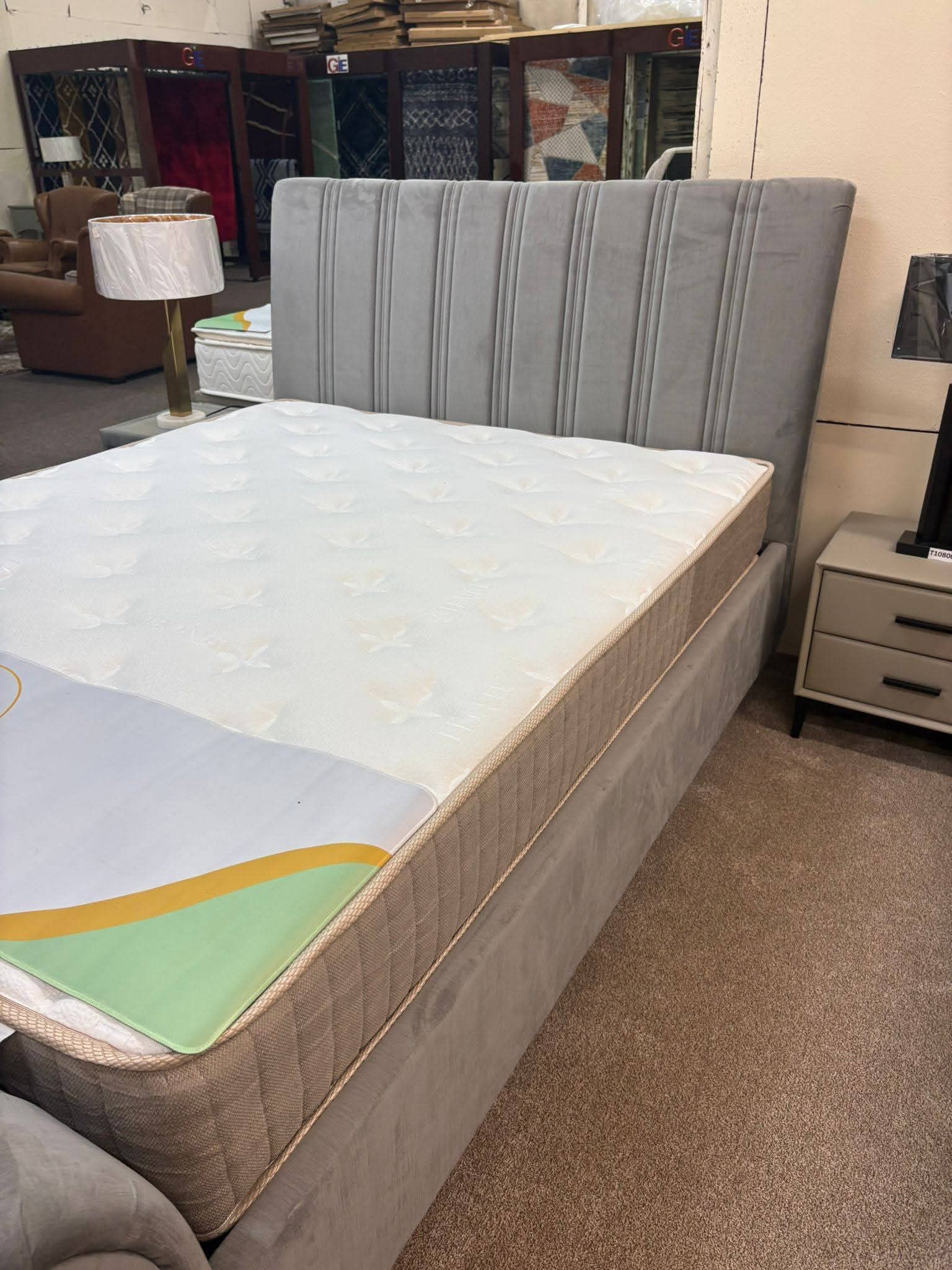 Modern gray upholstered bed with white mattress in a furniture showroom