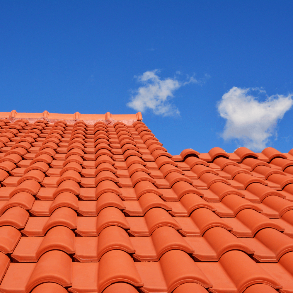 Terracotta roof tiles against a bright blue sky with a few white clouds