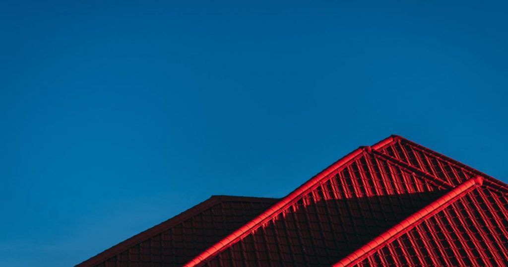 Red-lit geometric roof against a clear blue sky