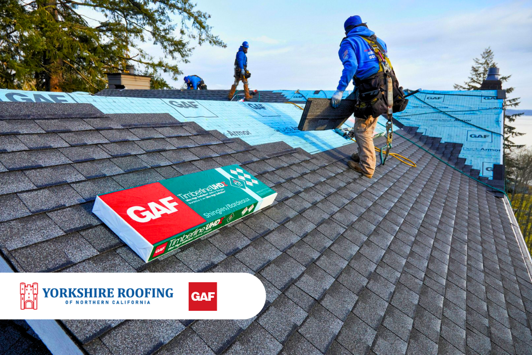 Workers installing blue roof shingles on a steep roof with GAF materials visible.