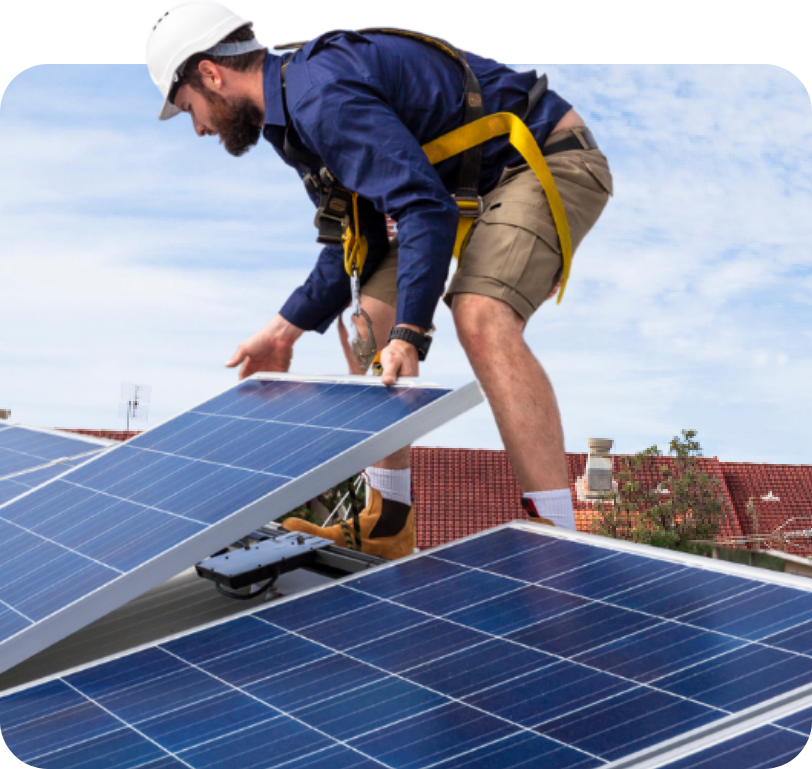 Worker installing solar panels on a rooftop under a blue sky
