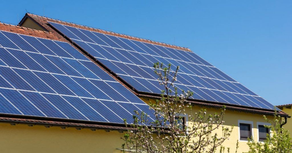 Roof covered with blue solar panels on a house under a clear sky