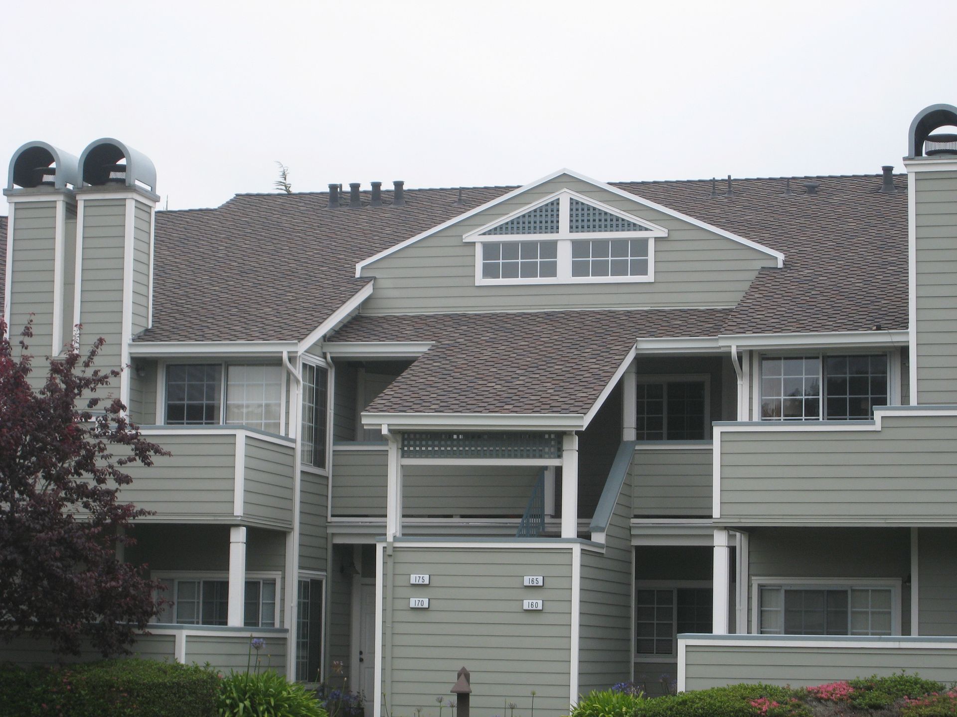 Exterior of a gray apartment building with balconies and a central gable roof