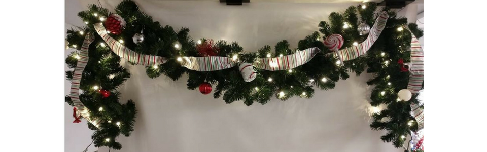 Christmas garland with red bows and lights draped over a white wall mantle