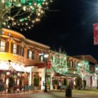 Festive night street scene with illuminated storefronts and hanging holiday lights