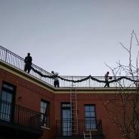 Two people on a rooftop above a brick building at dusk