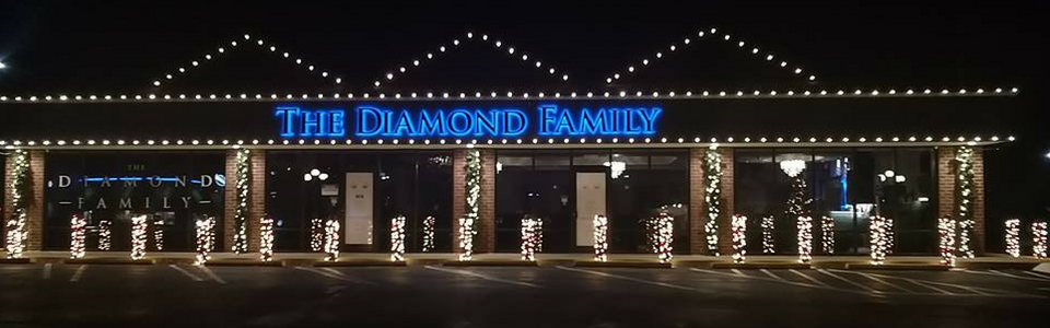 The Diamond Beauty storefront lit up at night with string lights and illuminated windows