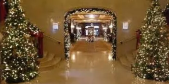 Festive hotel lobby with Christmas trees, garlands, and warm lights along a decorated corridor