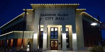 Night view of Dardene Prairie City Hall, lit warmly against a dark blue sky.