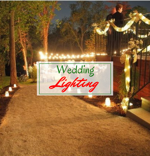 Wedding lighting on a decorated outdoor pathway at night, with warm string lights and candles.