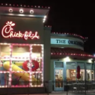 Night view of a Chick-fil-A storefront beside The Coffee Shop, both lit with colorful neon signs.