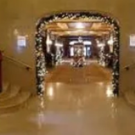 Decorated hotel corridor with gold walls and a bright archway leading to a dining area