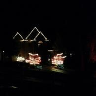 House lit with Christmas lights at night, with glowing decorations in the yard
