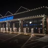Storefront at night with bright string lights and lit columns along the entrance