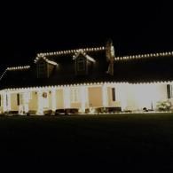 Well-lit house at night with bright exterior lights and dormer windows