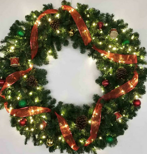Christmas wreath with green foliage, red ribbon, and warm white lights on a white background