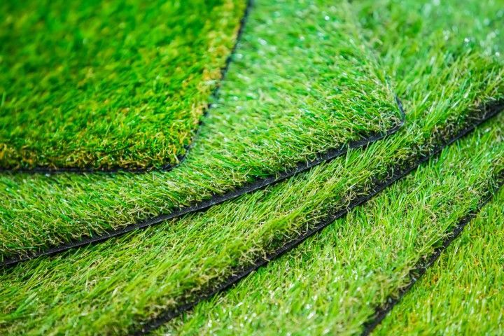 Stacked rectangular samples of vibrant green artificial turf with visible black backing edges.