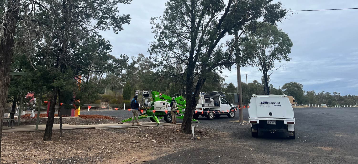 A Green Tree-trimming Machine and Service Trucks Parked — Rohr Electrical in Dubbo, NSW