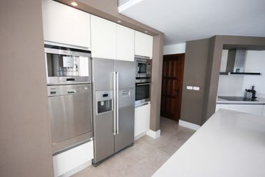 Modern kitchen with stainless steel appliances, white cabinets, and a light countertop.
