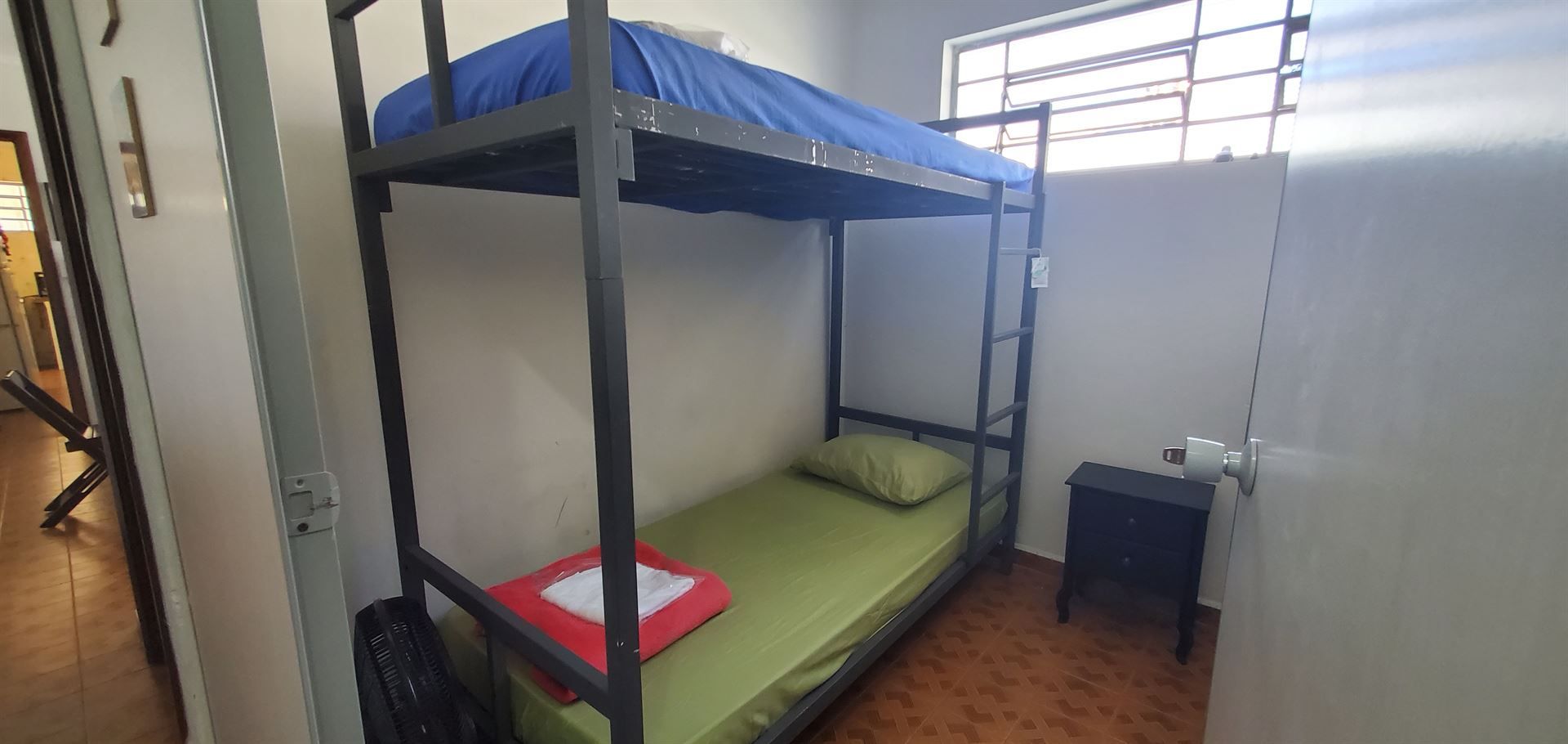 Um beliche fica em um pequeno quarto ao lado de uma janela.