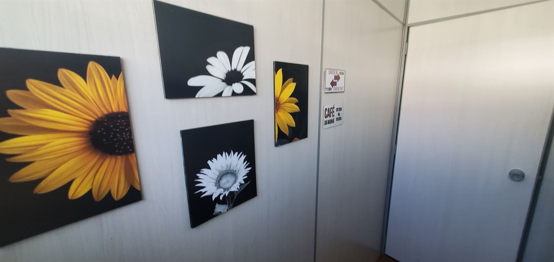 Três pinturas de girassóis estão penduradas na parede.