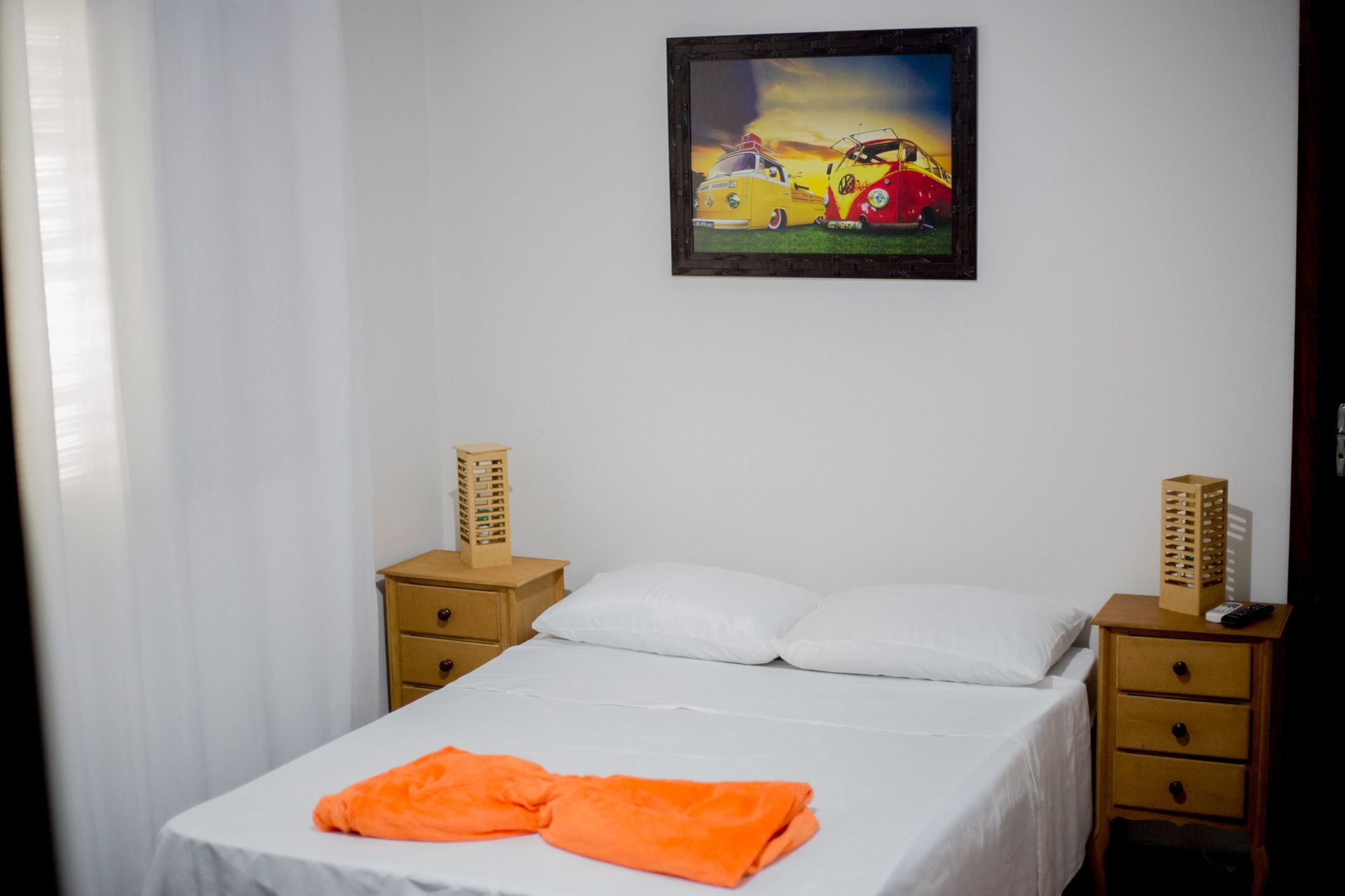 Um quarto com uma cama, duas mesas de cabeceira e uma pintura na parede acima da cama.