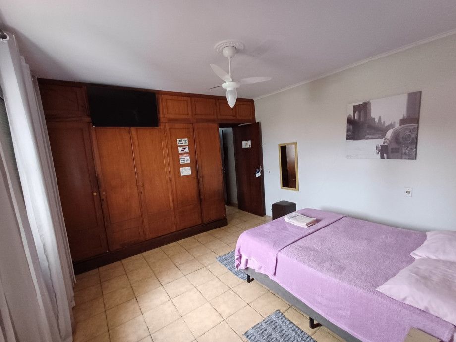 Um quarto com uma cama roxa e um ventilador de teto.